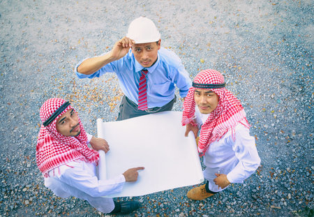 Arab businessman and engineers holding papar and discussing about plan of building site constructionの写真素材