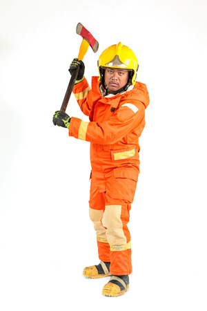 Firefighter in uniform and safety helmet standing holding axe full body length の写真素材