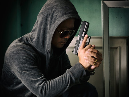 Hooded man with a gun in the dark room
