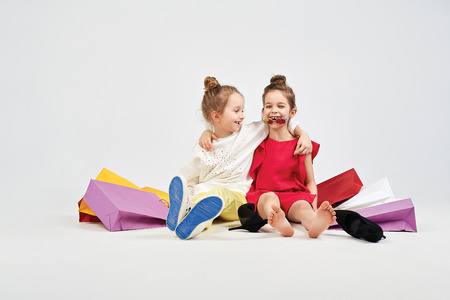 Laughing girls are sitting with shoppers bagsの写真素材