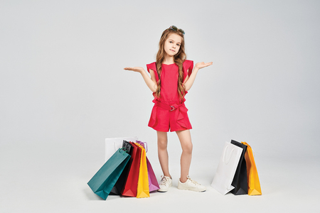 Little girl is standing around shoppers bagsの写真素材