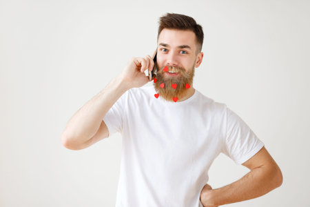 Positive pleasant looking bearded male model with long thick beard being satisfied to have phone...