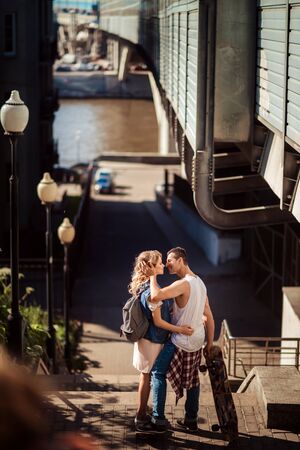 Street sport and hobby concept. Vertical shot of lovely couple of skaters have break after skating, embrace and going to kiss, enjoy togetherness and love. Active lifestyle and relationship concept.の写真素材