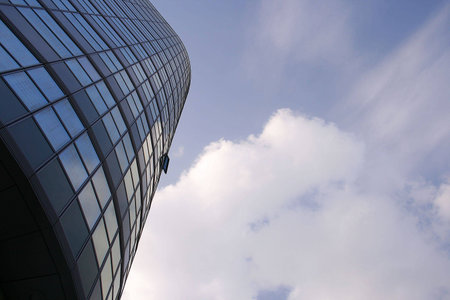glass office building with sky and clouds in the background