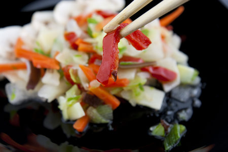 holding paprika with chopsticks above the plateの写真素材