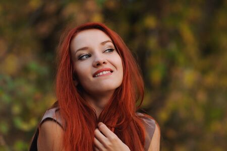 Outdoors portrait of beautiful young woman with red hair colorful autumnの写真素材