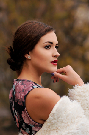 Outdoors portrait of beautiful young woman with big eyes and red lips, colorful autumnの写真素材
