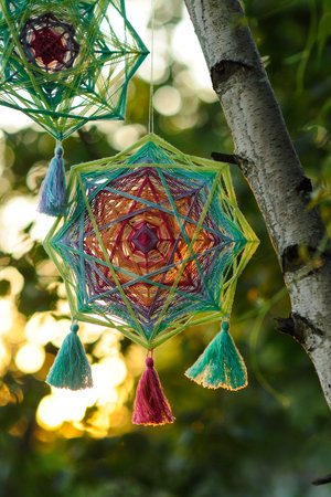 Woven colourful handcrafted yarn mandala outdoors in sunset timeの写真素材