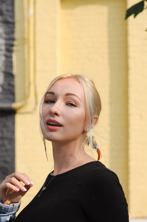 Close-up portrait of gorgeous blonde woman in boho chic feather earrings, bohemian jewelry