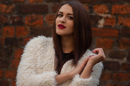 Glamor portrait of beautiful brunette lady with big eyes and red lips, wall background, Outdoors, colorful autumnの写真素材
