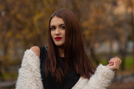 Glamor portrait of beautiful brunette lady with big eyes and red lips in park, Outdoors colorful autumnの写真素材