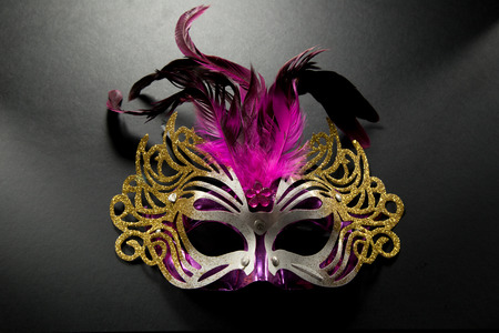 Carnival mask with pink feather on dark backgroudの写真素材