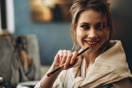 beautiful young girl holding brushes for drawingの写真素材