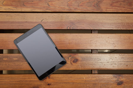 black tablet lying on a wooden table. workspace