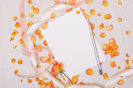 Creative mock up layout made of roses  with copy space on table homemade flat lay. Empty sheet of paper. Mockup with a card and orang roseの写真素材