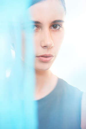Beautiful brunette girl on white and blue background. Beautiful face portraitの写真素材