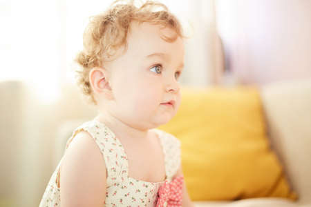 Little baby playing on at home. A small baby girl is left alone in her roomの写真素材
