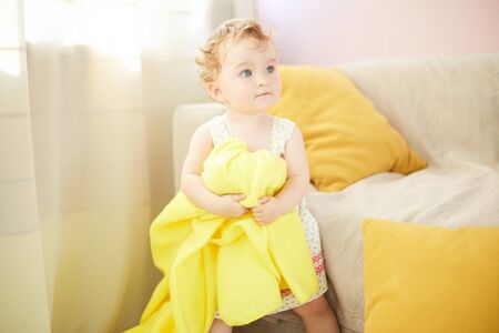 little child is playing in his room with a yellow blanketの写真素材