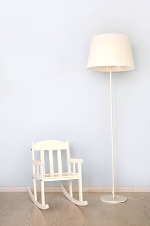 Modern interior with vintage lamp and white chair on wooden floor against bright wallの写真素材