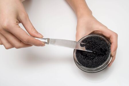 Black fish caviar. Female hands hold a knife. Shallow DOF, not isolation!の写真素材