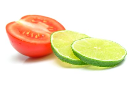 lime and a tomato on white. Isolation, shallow DOF.の写真素材
