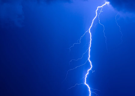 Photo of a lightning during a thunder-storm on a background of the dark dark blue skyの写真素材