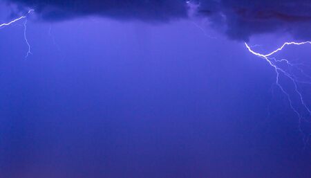 Photo of a lightning during a thunder-storm on a background of the dark dark blue skyの写真素材