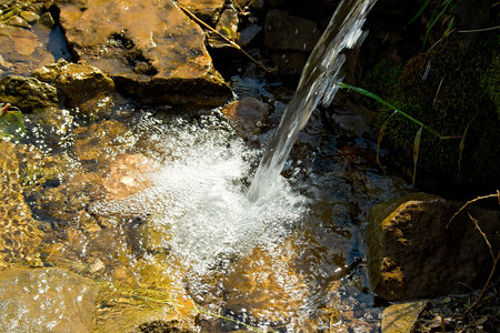 mountain spring emerges by the turbulent flow to the stones