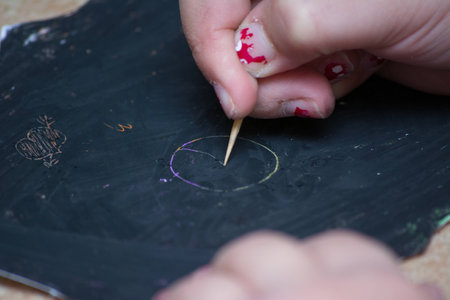 A kid's hand writing on a blackboard, scrached with stilusの写真素材