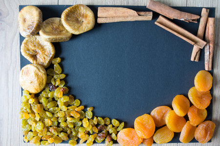 assorted dried, figs, raisins, dried apricots and cinnamon on a black backgroundの写真素材