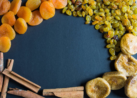 assorted dried, figs, raisins, dried apricots and cinnamon on a black backgroundの写真素材