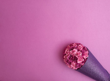 Bouquet of light and dark purple roses in glittering violet paper on a purple background. Text...