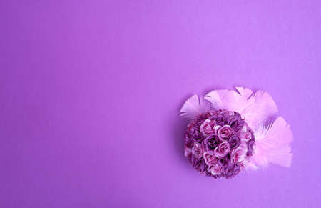 Purple bouquet of artificial roses on pink feathers on a purple violet background. Text space. Celebrations, weddings, Valentine's Day. Minimal style. Top view. Flat lay.の写真素材