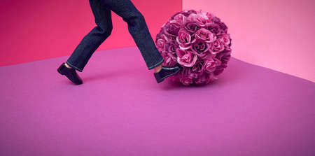 Purple pink background. A man kicks a bouquet of artificial roses. Text space. Disappointment, emotion, engagement, wedding, valentine, concept. Minimal style.の写真素材