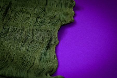 Olive green scarf on a purple background. Text space. Decorations, fashion, arranging, background...