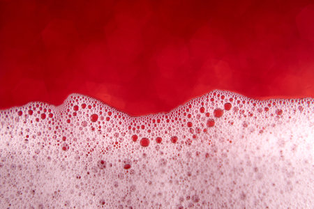 Soap foam with bubbles on a blurred red background. Closeup.の写真素材