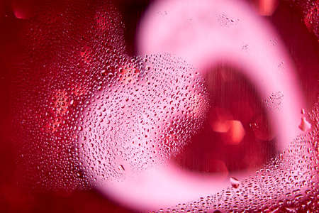 Heart-shaped drops on a blurred shiny red-white background.の写真素材