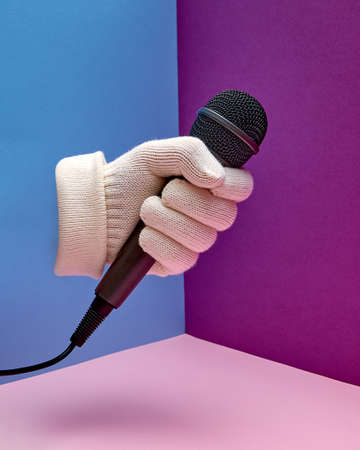 A hand in a white glove holds a microphone. Podcast. Hand gesture.の写真素材