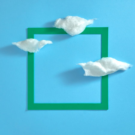 White clouds and a green square frame on a light blue background. Template. Text space. Top view....