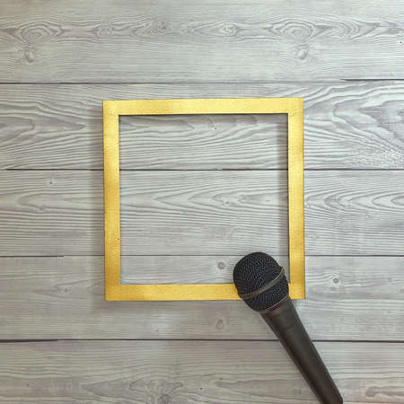 Microphone and gold frame on a gray wooden background. Text space. Top view. Minimal style. Podcast, voice, broadcast.の写真素材