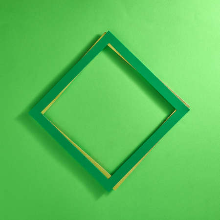 Green frame over gold frame on pastel green background. Text space. Top view. Minimal style.の写真素材