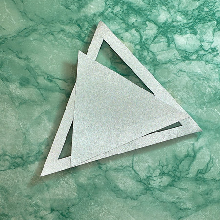Silver triangle on a silver frame. Green marble background. Text space. Top view. Minimal style.