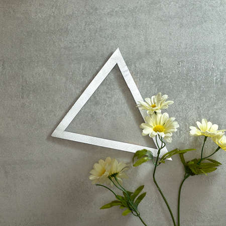 White flowers, daisy, and a silver triangular frame on a gray concrete background. Text space. Top view. Minimal style.の写真素材