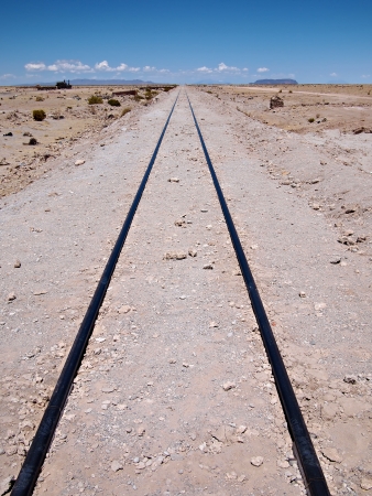 Railroad track leading far away in the distance in the desert at the train graveyard of Uyuni in Bolivia の写真素材