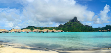 Panorama view on luxury overwater bungalows in a vacation resort in the clear blue lagoon with in...
