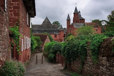View on a path leading towards the tower of the church in red stone in the red village Collonges-la-Rouge in Dordogne area, Limousin, France.のeditorial素材