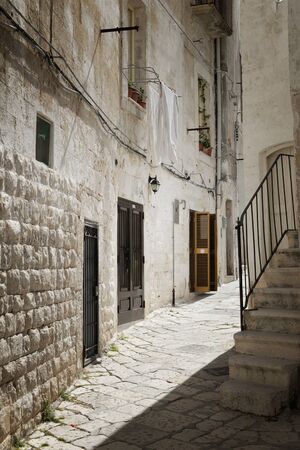 Laundry day in Italy with white blankets hanging to dry from a stone house in a cobblestone alley in an old Italian city.の写真素材