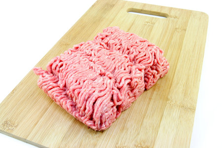 A block of minced meat on a wooden chopping board on a white background