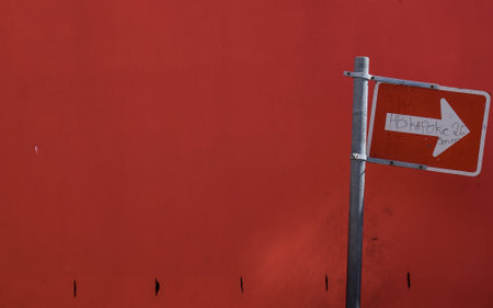 White arrow street sign in front of red wall