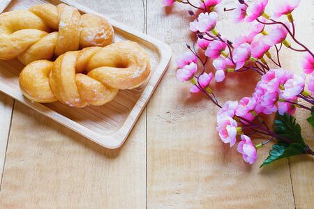 Bread, sugar-coated and flowers on a wooden table.の写真素材